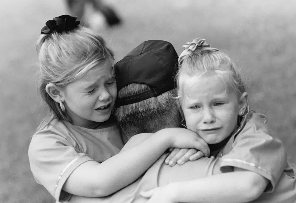 Association APTE, photo d'illustration d'un papa avec ses deux enfants dans les bras tristes